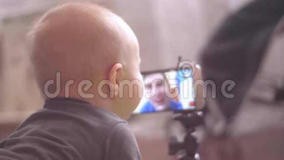 小男孩看着他父亲的视频和触摸智能手机屏幕4K后视景特写镜头视频的预览图