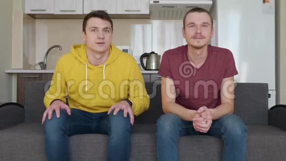 两个人坐在沙发上看电视上的足球比赛支持不同的球队视频的预览图