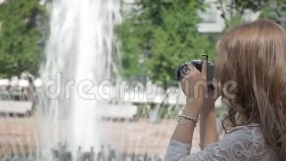 美丽的女孩正在一台老式相机上拍摄城市喷泉的照片视频的预览图