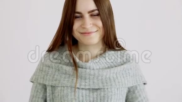 穿着一件暖和的毛衣的美丽的欧洲女孩站在白色的墙上情绪快乐和笑声视频的预览图
