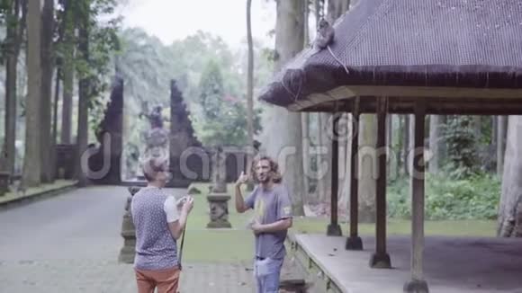 两个年轻的游客站在木树旁照猴子视频的预览图
