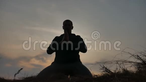 宗教观念一位在日落阳光下冥想的男僧的剪影佛教生活方式祈祷视频的预览图