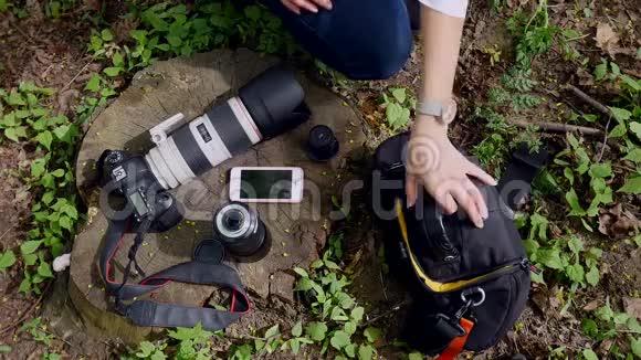 相机和电话躺在草地上摄影师把所有的东西都收在袋子里视频的预览图