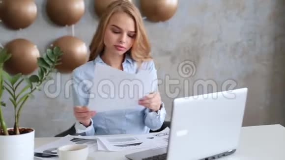 年轻的女商人坐在工作场所在办公室看报纸视频的预览图