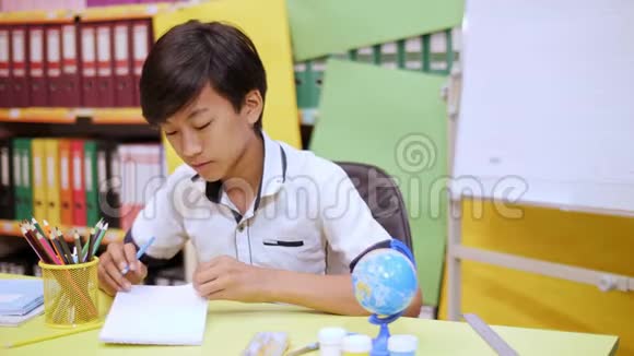 那个男孩坐在桌子旁用手指指着笔记本的页视频的预览图