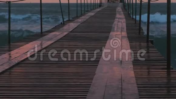 波浪在木墩上溅出美丽的海景晚上有粉红色的日落码头和风暴波视频的预览图