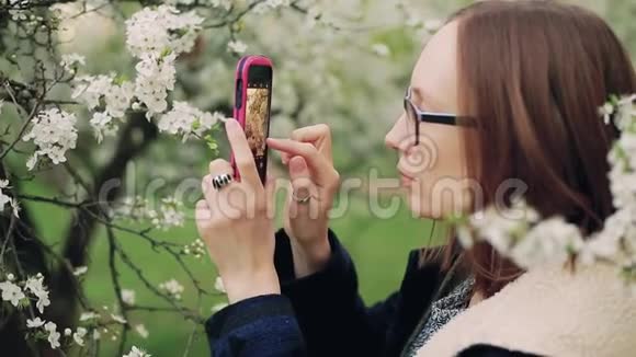 偶然的女人在智能手机上拍摄春天的花朵视频的预览图