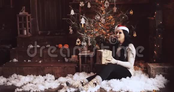 戴圣诞礼帽的女人坐在圣诞树旁视频的预览图