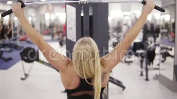 迷人的金发白种人女人肌肉发达背部有纹身在拿着拉马什上锻炼视频的预览图