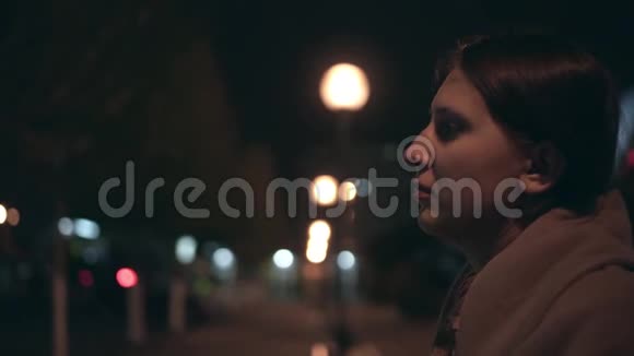 疲惫的女孩穿着米色外套头发破烂下班后走在黑暗的街道上视频的预览图