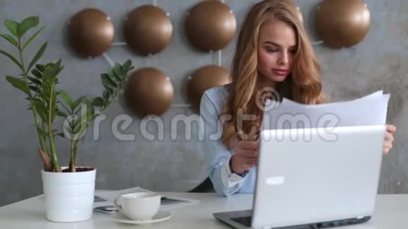 有笔记本电脑的女商人的肖像写在她办公室的一份文件上视频的预览图