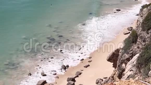 从岩石悬崖向海浪和岩石海滩眺望视频的预览图