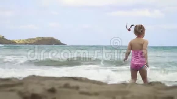 在一个美丽的日子里小女孩在海浪中漫步视频的预览图
