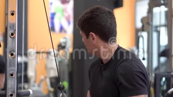 年轻健康的肌肉男在现代健身中心做三头肌下拉绳伸展运动视频的预览图