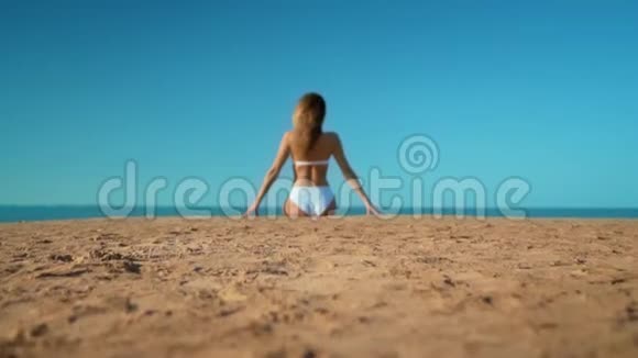 穿着白色泳衣坐在大海背景上的美丽女孩视频的预览图