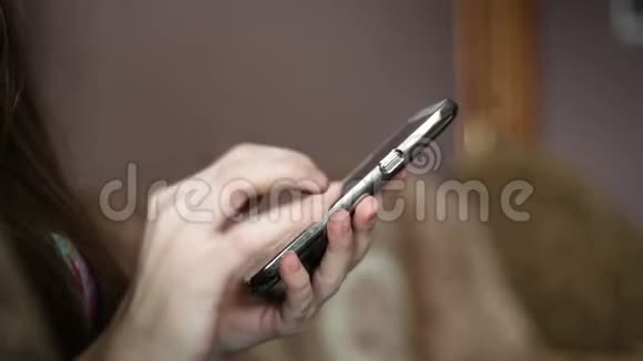 漂亮的年轻女人坐在家里的沙发上用电话女人上网社交网络寻找一些东西视频的预览图