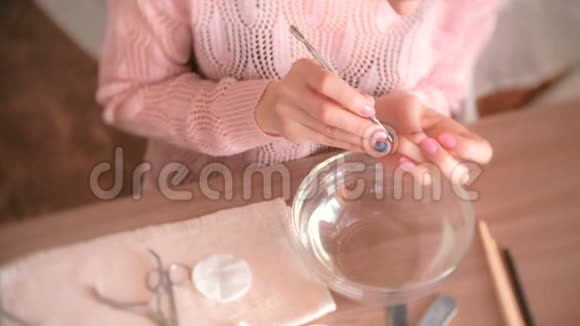 女人用推杆去除角质层自己修指甲特写双手手术工具放在桌子上上景视频的预览图
