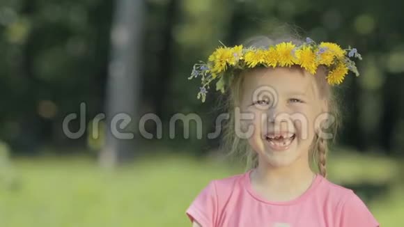树林里一个有趣的小女孩的肖像一个没有门牙的孩子看着镜头笑了在头上视频的预览图