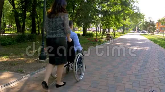 坐轮椅的年轻人和妻子在户外散步视频的预览图