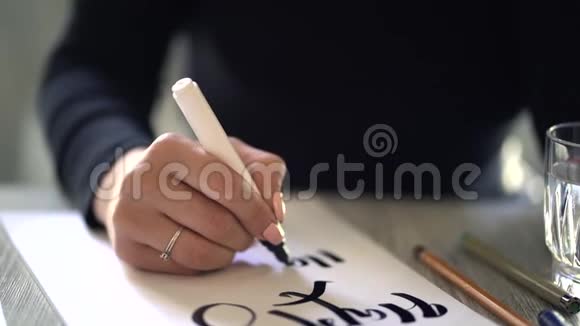 年轻的设计师他的手在白纸上写短语刻划装饰的字母书法图形视频的预览图
