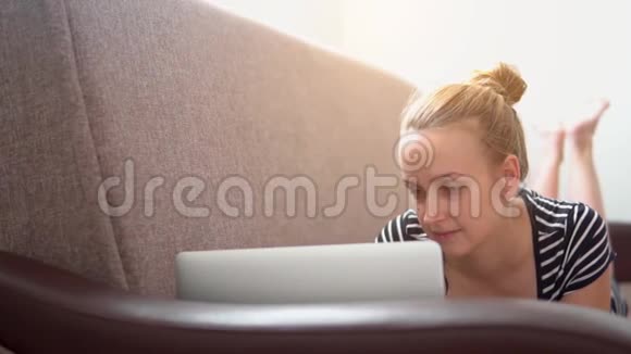 女人在沙发上放松在笔记本电脑上工作慢动作视频视频的预览图
