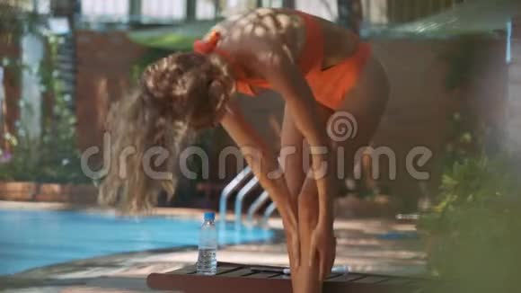 游泳池边的女孩用防晒霜保护身体涂抹的腿视频的预览图