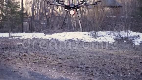 在深秋森林背景下一架带有起落架的直升机向地面飞行剪辑小型黑色无人机视频的预览图