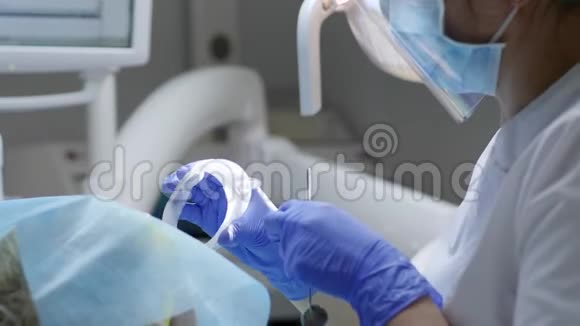 牙科医生用镜子检查口腔病变并在牙科医生办公室附近用无菌餐巾纸面部视频的预览图