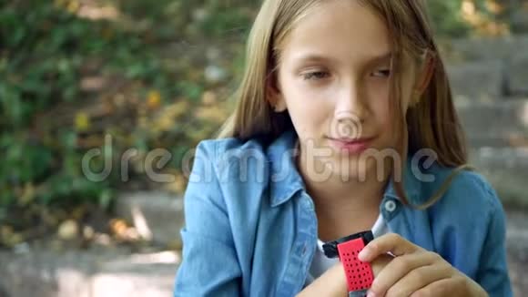 智能手表儿童在公园户外使用智能手表儿童在智能手机上交谈视频的预览图