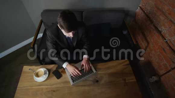 年轻的商人用笔记本电脑和客户交谈在咖啡馆的桌子上顶部视图视频的预览图