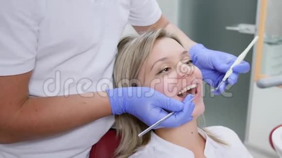 医生诊所一位在牙科诊所张口的美女用手中的牙科器械进行检查视频的预览图