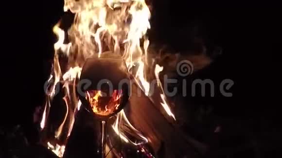 一杯酒和烟雾中的火反射晚上的篝火慢动作背景视频的预览图