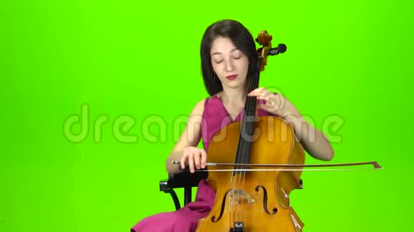 穿裙子的女孩玩大提琴绿色屏幕视频的预览图