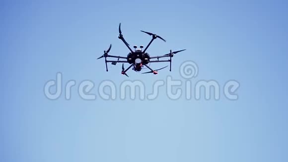 四架直升机无人机盘旋在晴朗的蓝天视频和照片拍摄的概念剪辑黑色小四转子与视频的预览图