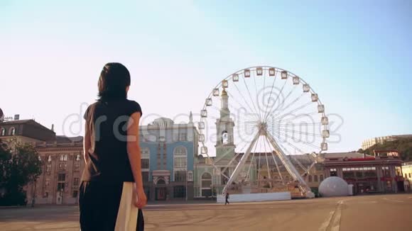 女人走到市场广场的摩天轮前视频的预览图