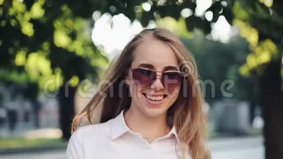 漂亮的微笑年轻女子穿着时尚的服装自信地走在街上戴着太阳镜充满活力的生活乐趣视频的预览图