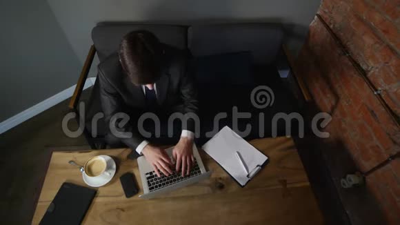 商人在笔记本电脑上工作在咖啡馆里喝咖啡商人为胜利而高兴顶部视图视频的预览图