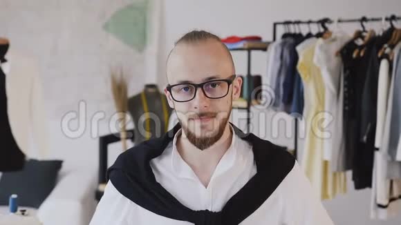 一个留胡子的裁缝在眼镜与制作使用卷尺在阿泰利耶概念时装设计师视频的预览图