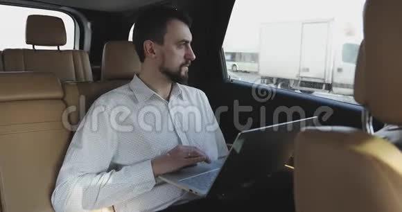 一个留着胡须的商人在旅行时在笔记本电脑上工作然后看着窗外视频的预览图