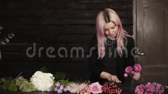 一位有着粉红色头发的迷人花店把桌上的花整理好为将来的插花挑选视频的预览图
