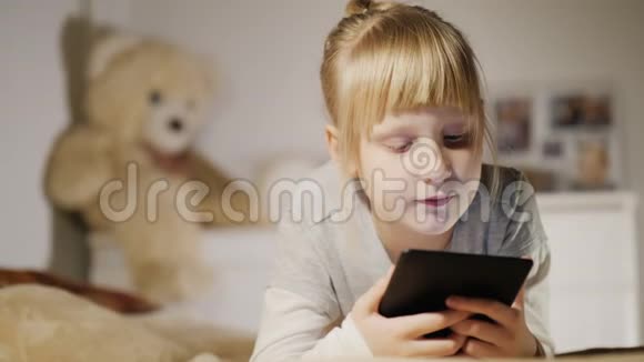 一个6岁的女孩在卧室里读一本电子书视频的预览图