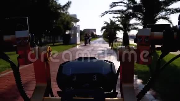 在度假小镇的红自行车道上骑电动自行车上面有棕榈树视频的预览图
