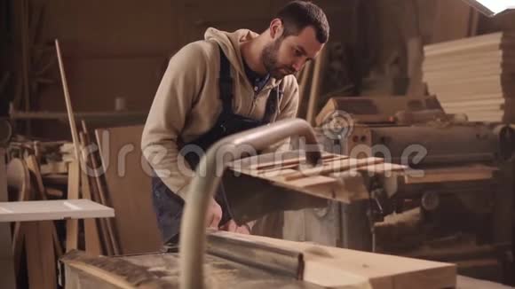 这位工匠正在生产电锯机锯一根大木条尘埃和碎片散射视频的预览图