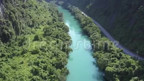 峡谷中丛林河流和公路上方的空中运动视频的预览图