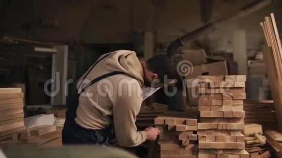 一个人在木工车间里拿着一块平板电脑和一支钢笔数着木块的数量乔特在工作视频的预览图