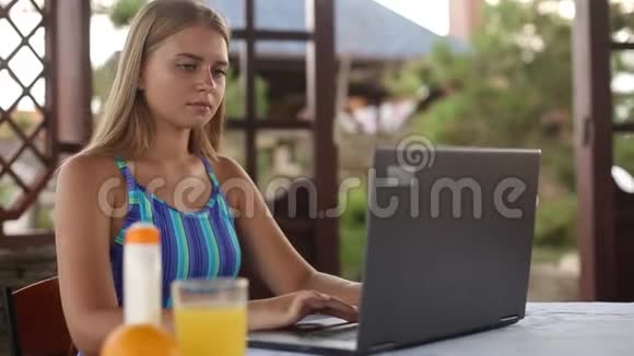 自由舞者的女人坐在热带夏季的花园房子里穿着泳衣远程使用笔记本电脑视频的预览图