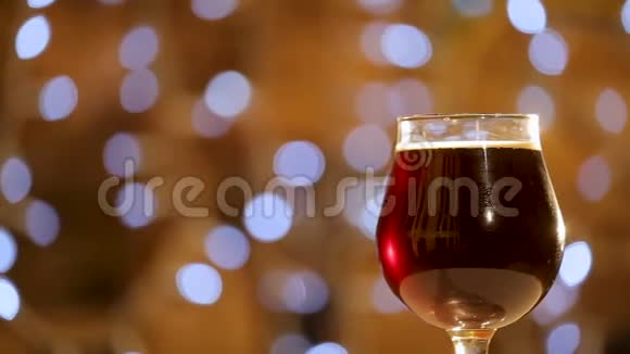 一杯黑啤酒慢慢地绕着它的轴转啤酒泡沫上升到啤酒泡沫视频的预览图