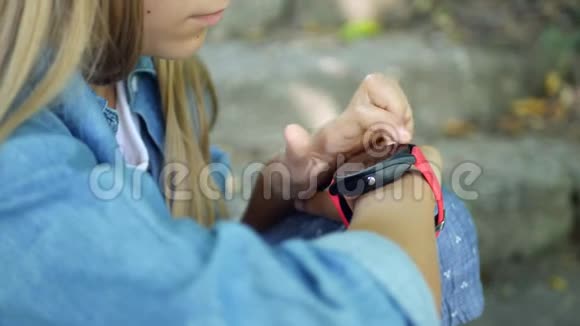 智能手表儿童在公园户外使用智能手表儿童在智能手机上玩耍视频的预览图