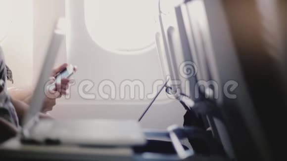 飞机乘客在飞行过程中使用各种移动设备智能手机和触摸屏笔记本电脑的近距离侧视图视频的预览图