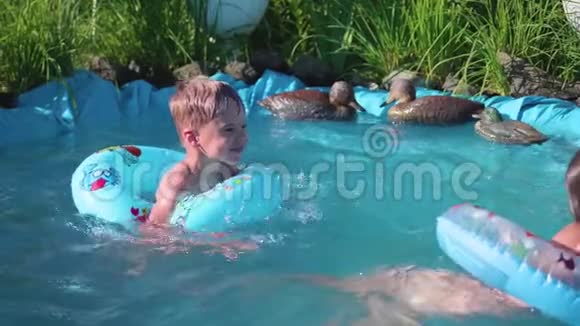 两个小朋友在一个小池塘里游泳兄妹笑泼水孩子们在炎热的夏日游泳视频的预览图